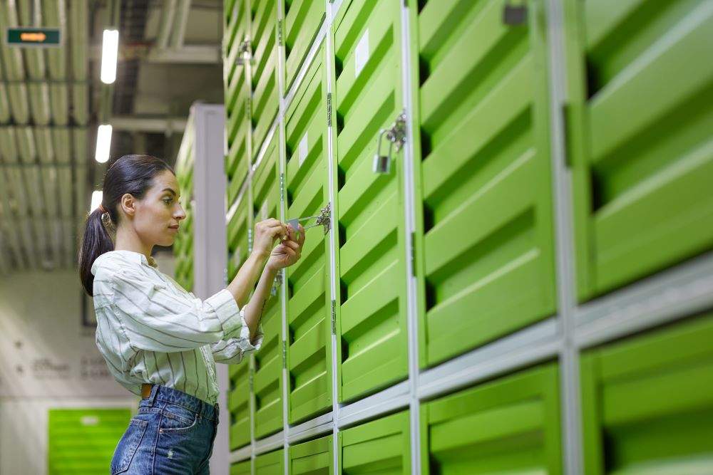 A woman sliding open the door of a large storage unit in a well-lit facility