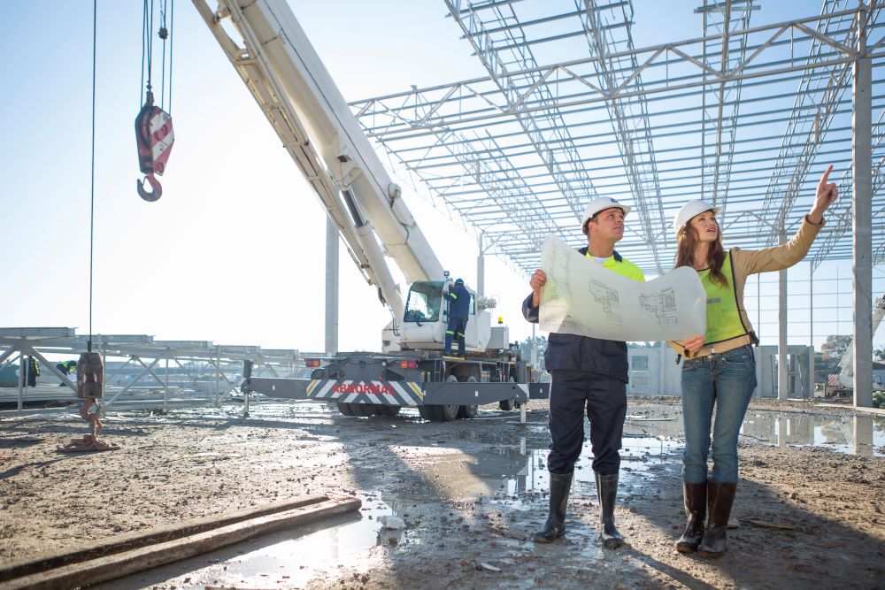 Site manager and architect checking blueprint on construction site